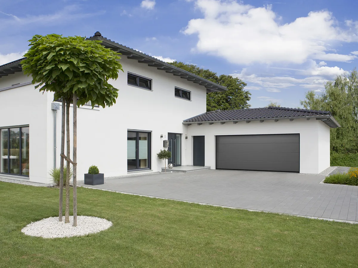 Normstahl Superior Doppelgaragentor in Graualuminium an einem weißen Einfamilienhaus mit Walmdach