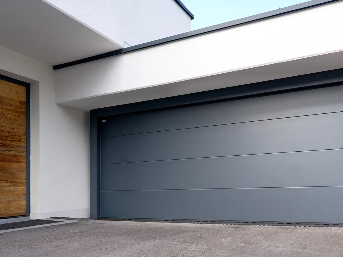 Normstahl Superior Sektionaltor in Graualuminium, Detailansicht mit Holzhaustür daneben